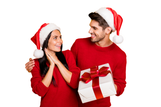Portrait of handsome man in xmas hat give package to his impressed wife wear red pullover isolated over yellow background