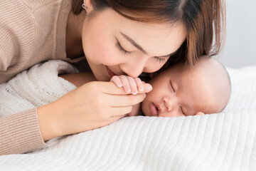 Asian beautiful mother motherhood lie down nursing, kissing newborn baby, gently hold infant together, love bonding at first site, toddler sleep leisure comfortable, healthcare and medical taking care