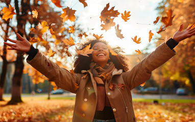 Casual joyful woman having fun throwing leaves in autumn at city park