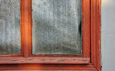 old wooden framed window covered with reflective foil blind