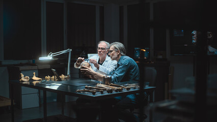 Two archaeologists take measurements of ancient human skull, conduct historical research, use...