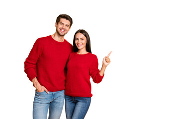 Portrait of charming married couple point at copy space recommend ads wear red pullover denim jeans...