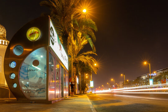 Dubai, UAE, 27.09.21. Air-conditioned RTA bus stop in Dubai at night on a busy road, with car lights streaks and palm trees, long exposure photo.