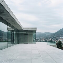 Modern minimalist architecture of a concrete and glass building overlooking a serene landscape on a cloudy day