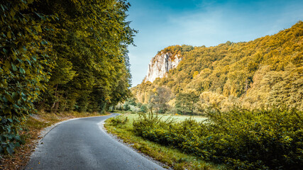 Beautiful autumn landscape. The setting sun illuminating the limestone rocks. An asphalt road winding through the valley. Bedkowska Valley. Jura. Poland