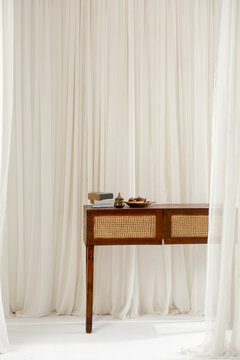 Wooden table in front of white curtains