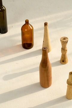 Glass bottles of different size placed on a white floor with shadows forming