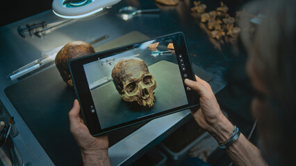 Archaeologist takes photo of fossil remains of prehistoric extinct human skull on work surface...