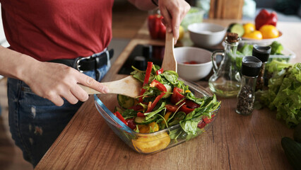 Girl Mixing Fresh Healthy Vegetable Salad In The Bowl On The Kitchen Table