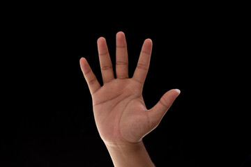 Close-up of palm with five fingers spread showing number 5, waving or stop. Photo isolated on black...