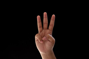 Close-up of one hand showing the number three. Photo isolated on black background