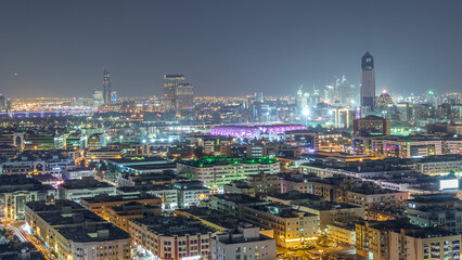 Fototapeta premium Aerial view of neighborhood Deira with typical buildings night timelapse, Dubai, United Arab Emirates