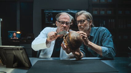 Two archaeologists talk and study skull of ancient extinct human, conduct historical and scientific...