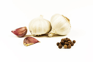 Two heads and cloves of garlic with pepper on a white background