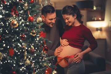 Excited young adult parents expecting a new family member and celebrating Christmas