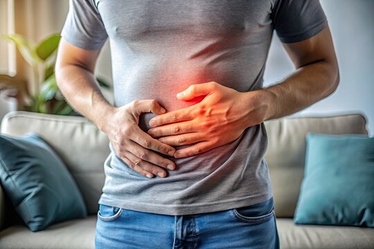 A clenched hand grasps a tender abdomen, as a faintly visible outline of a couch in the blurred background suggests a day ruined by digestive discomfort.