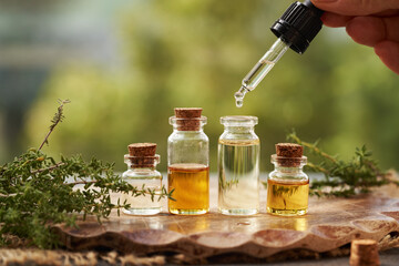 Drop of aromatherapy essential oil falling from a pipette into a bottle outdoors
