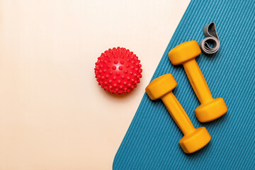 Flat lay of fitness equipment with dumbbells, a elastic band, and massage ball