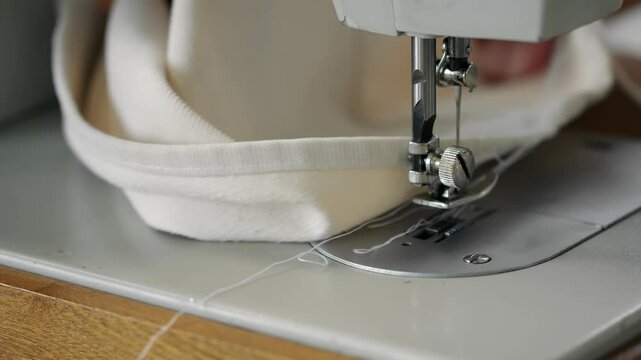 Close-up of women's hands sewing fabric on a sewing machine