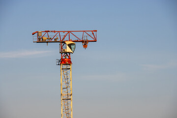 Close-up of a crane being assembled, with the cabin in place but without the boom, set against the...