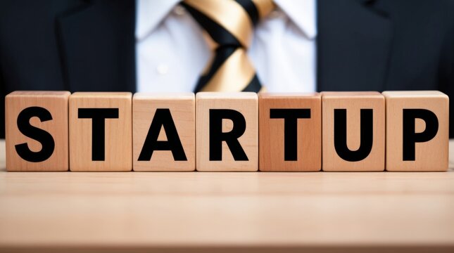 Wooden blocks with the word startup, person wearing a suit in the background, business and innovation concept.