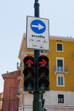 The road sigh white arrow showing direction above the traffic light in the Italian town