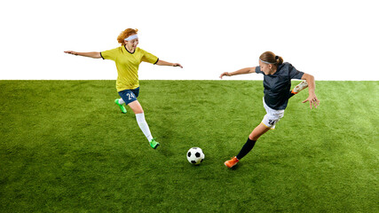 Naklejka premium Two young women, intense soccer players, airborne and in action on green field, each trying to outmaneuver other for ball control. Concept of sport, competition, tournament, games, event.