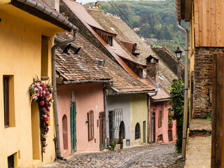 Uphill view on empty Sighisoara street with colorful medieval houses, Romania