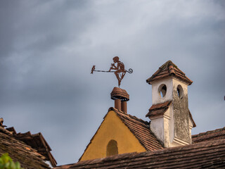 Sighisoara, Romania, August 27, 2024 : Weathervane in the form of a boy with a pipe and a bird on the roof of a dwelling house in the old city of Sighisoara in Romania