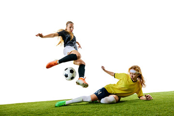 Young female soccer player, mid-20s, jumping to avoid sliding tackle by her opponent, both fully committed on green soccer field. Concept of sport, competition, tournament, games, event.