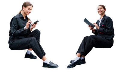 Two young professional women in black attire, sitting and engaging with technology, smiling...