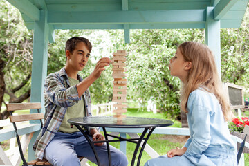 boy in a blue checkered shirt and jeans and a girl in a blue sweater and blue trousers are intently...