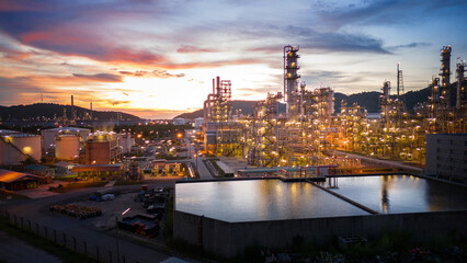 Fototapeta premium Oil Refinery plant at sunset. Gas Chemical Equipment Prodiction import export Concept, Crude Oil Refinery Plant Steel Pump Pipe line and Chimney and Cooling tower, Chemical Petrochemical