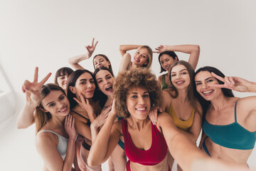 Studio no retouch photo tender funny ladies dressed lingerie recording vlog showing v-sign enjoying self acceptance isolated beige color wall background