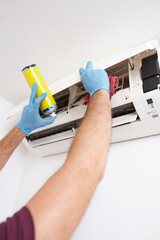 Man cleaning and maintaining air condition unit at home.