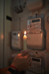 Checking the electricity power meter with a candle in cold winter days while there is power outage.