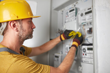 Technician working on a modern electricity power meter station in a building.