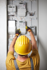 Technician working on a modern electricity power meter station in a building.