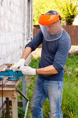 Diligent efficient  worker makes repairs  with electric tools  hammer and  pliers in backyard of house