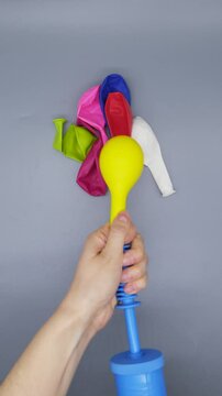 Female hands inflate a yellow balloon using a pump