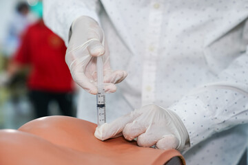Nursing students practice injections on a training model, focusing on precise technique while wearing gloves and masks.
