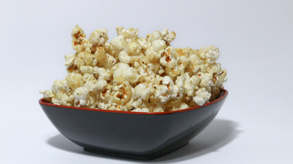 Caramel Popcorn in black bowl isolated on white background.