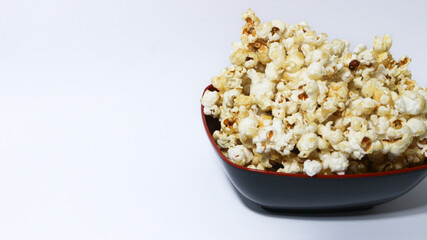 Caramel Popcorn in black bowl isolated on white background.