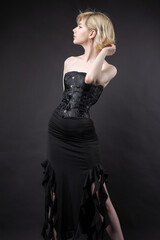 Naklejka premium Expressive young blonde under a bob in the studio. In a black corset and dress.