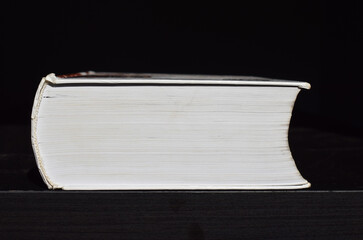 A thick book on a black table on a black background.
