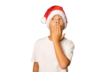 Little boy celebrating christmas day wearing a santa hat isolated shocked covering mouth with hands over transparent background.