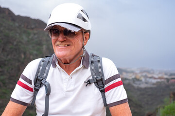 Portrait of smiling senior hiker man wearing protective helmets walking on mountain excursion enjoying freedom and nature. Freedom, success sport concept
