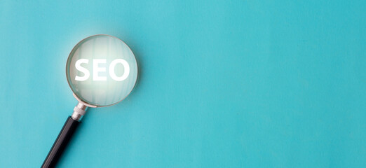 close up top view on magnify glass with word SEO (search engine optimization) on blue color...