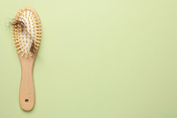 One brush with lost hair on light olive background, top view. Space for text