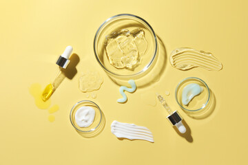Petri dishes with cosmetic products and pipettes on yellow background, flat lay